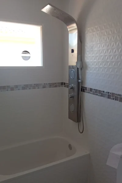 Instalación de bañera con columna de ducha de hidromasaje en acero inoxidable y alicatado blanco en Málaga por REFORMAS A Plomo y Nivel