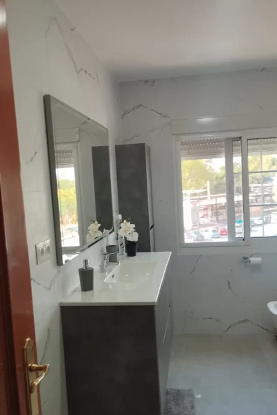 Reforma integral de baño en Málaga con alicatado imitacion marmol, mueble de lavabo moderno y espejo por REFORMAS A Plomo y Nivel